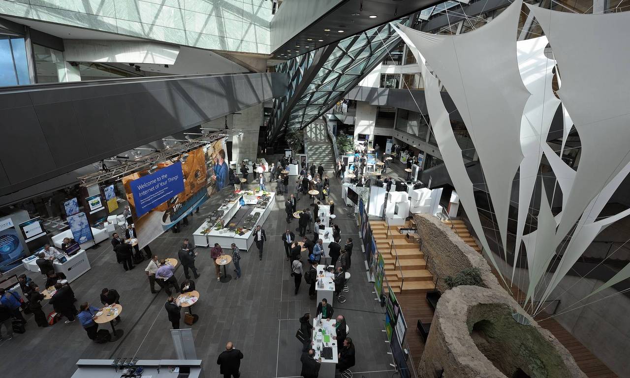 Die Aufnahme zeigt eine Veranstaltung im darmstadtium von oben. Im atrium sind auf der rechten und linken Seite Messestände aufgebaut, an denen Besucher stehen. In der Mitte des atriums befinden sich Stehtische und ein Informationsstand. Am rechten Bildrand befindet sich die Stadtmauer und die Zisterne des Lichtes.